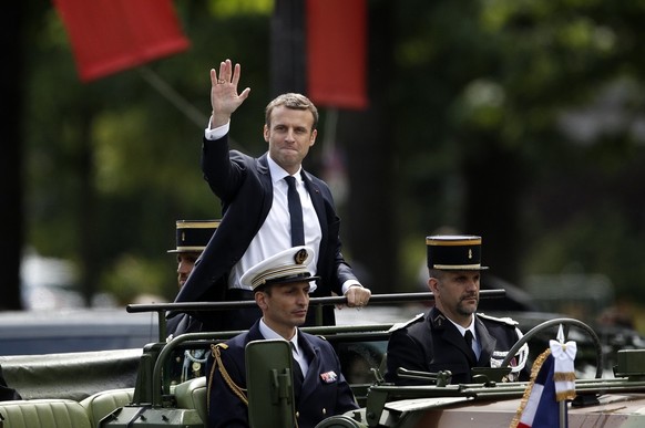 epa05963337 New French President Emmanuel Macron (C) waves from a military car as he is driven on the famous Champs Elysee boulevard after the handover ceremony in Paris, France, 14 May 2017. EPA/YOAN ...