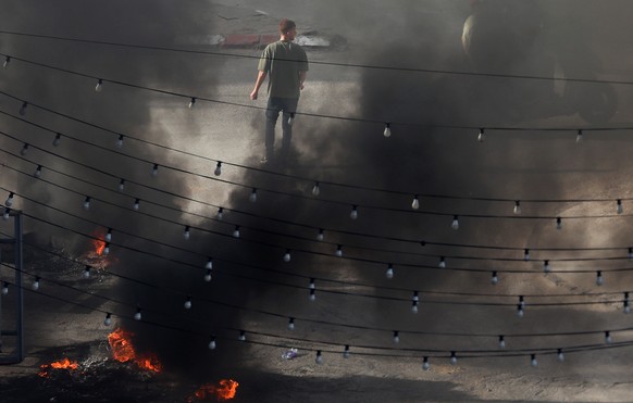 epa11358243 A Palestinian man walks past rising smoke during an Israeli army raid in the Jenin refugee camp, 21 May 2024. At least seven Palestinians including a doctor, a schoolteacher and two studen ...