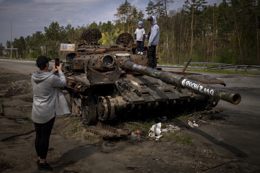 Des passants se prennent en photo devant l&#039;épave d&#039;un char russe, près de Kiev.