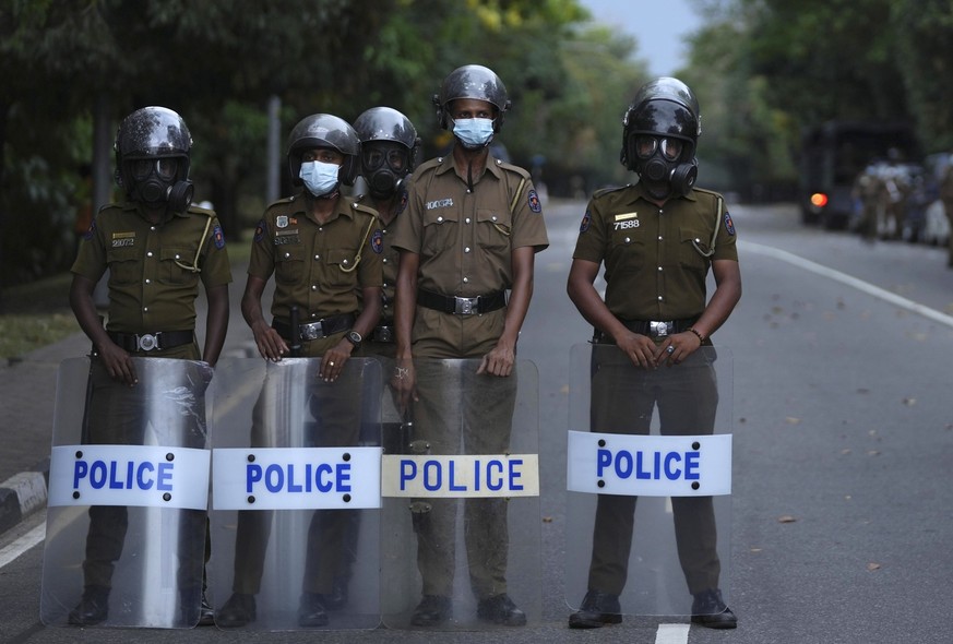 Sri Lankan police officers stand guard near the parliament during a protest in Colombo, Sri Lanka, Tuesday, April 5, 2022. A group of Sri Lankan governing party lawmakers called Tuesday for the appoin ...