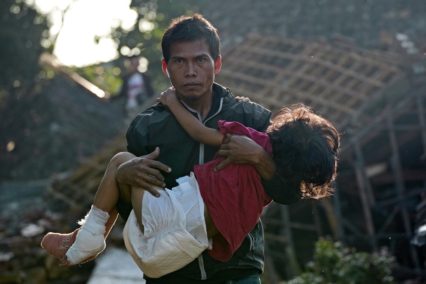 A man carries his injured daughter as they head to a temporary shelter for those displaced by Monday's earthquake in Cianjur, West Java, Indonesia, Thursday, Nov. 24, 2022. The 5.6 magnitude earthquak ...