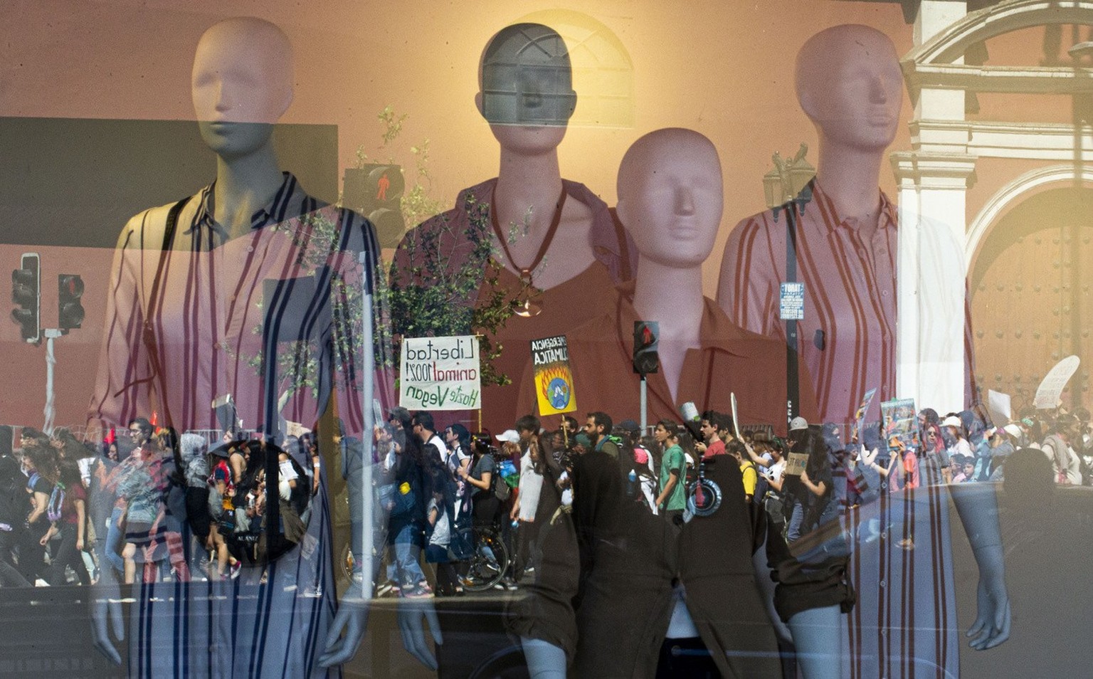 Demonstrators taking part in a global protest on climate change are reflected in a clothing store window, in Santiago, Chile, Friday, Sept. 20, 2019. Across the globe, hundreds of thousands took to th ...