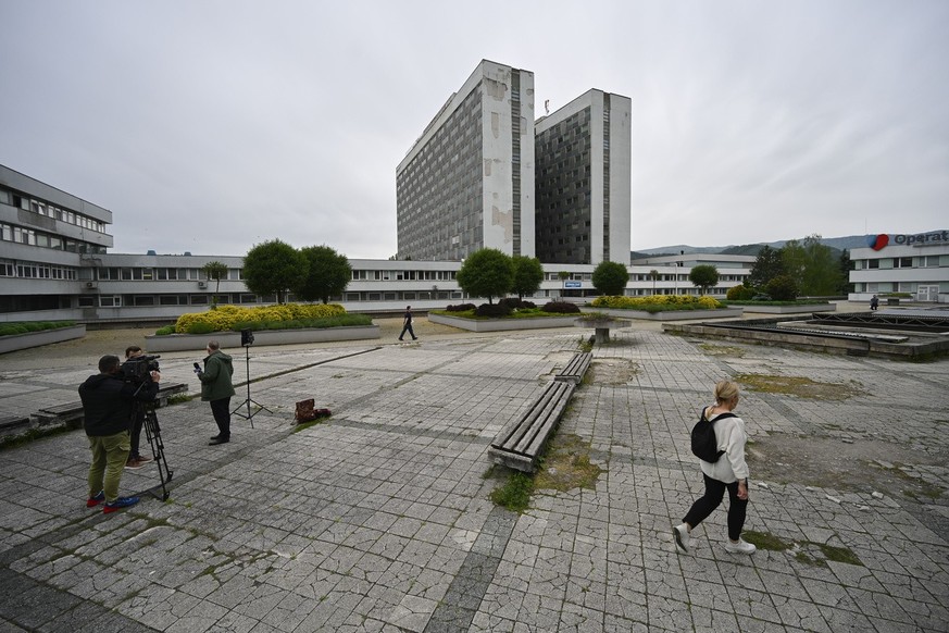 A woman walks next to camera news crew outside the F. D. Roosevelt University Hospital, where Slovak Prime Minister Robert Fico, who was shot and injured, is treated, in Banska Bystrica, central Slova ...