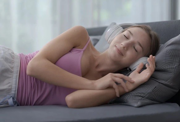 Les sons binauraux, dont les fréquences diffèrent légèrement, sont censés favoriser la relaxation du cerveau. Une jeune femme écoute des sons relaxants sur son lit.