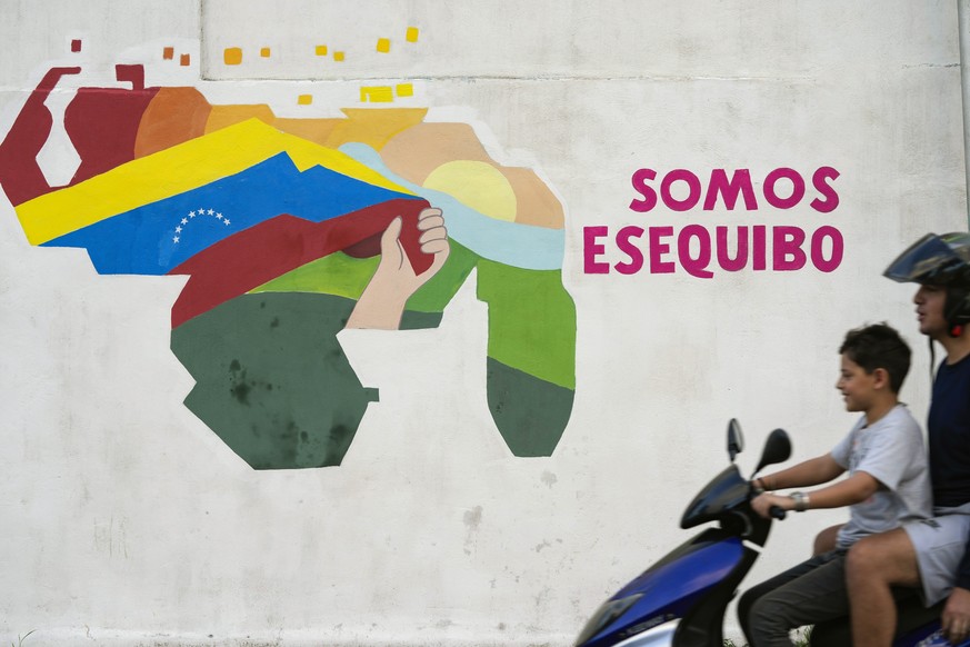 FILE - A boy drives a motorcycle in front of a mural of the Venezuelan map with the Essequibo territory included in the 23 de Enero neighborhood of Caracas, Venezuela, Monday, Dec. 11, 2023. Venezuela ...