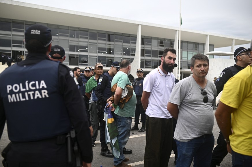 La police militaire menotte des partisans de l'ex-président brésilien Jair Bolsonaro, lors des émeutes du 8 janvier.