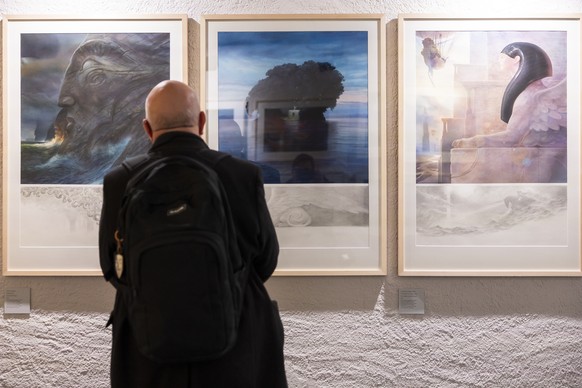 epa12593996 A visitor looks at artwork on display the inaugural exhibition of 'Journey into the Worlds of John Howe' at the Tour du Fantastique in Neuchatel, Switzerland, 15 December 2025. T ...