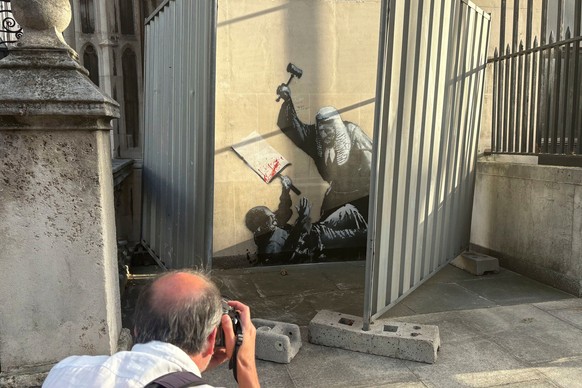 A person photographs a new artwork by Banksy which portrays a judge beating a protester with a gavel at the Royal Courts of Justice in London, Monday Sept. 8, 2025. (Callum Parke/PA via AP)
Britain Ba ...