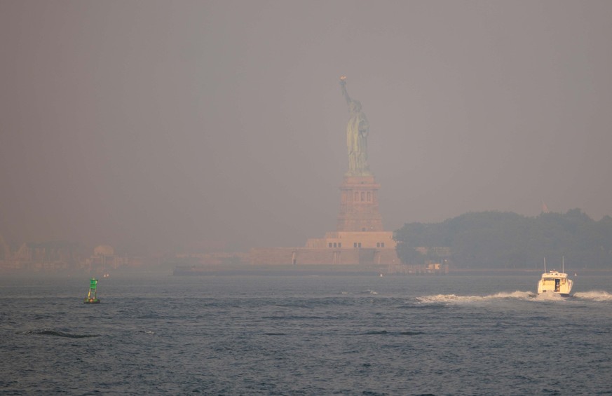 NEW YORK, NEW YORK - JULY 17: Haze from Canadian wildfires obscures the Statue of Liberty as seen from Brooklyn Bridge Park on July 17, 2026 in New York City. New York City has been under an Air Quali ...