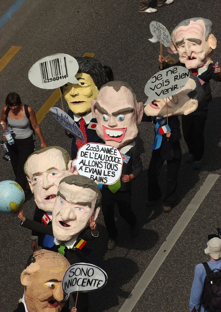 Protestors wearing masks of head of states and carrying banners walk through the streets of Geneva, Sunday, June 1, 2003. Around 15'000 anti G8 protestors gathered in Geneva and walked towards th ...