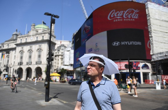 epa10079570 A man uses an umbrella hat to shelter from the sun in London, Britain, 19 July 2022. The Met Office has issued a red extreme heat warning as the UK could have its hottest day on record thi ...