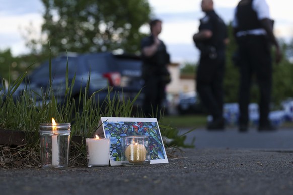Police walk by a small memorial as they investigate after a shooting at a supermarket on Saturday, May 14, 2022, in Buffalo, N.Y. (AP Photo/Joshua Bessex)