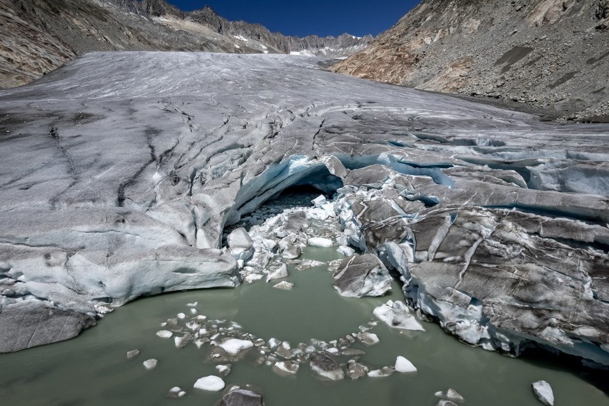 (FILES) This photograph shows a group of hikers making their way past a melt hole on the melting Rh�ne Glacier, above Gletsch in the Swiss Alps, on July 24, 2026. Swiss glaciers have lost nearly 20% o ...