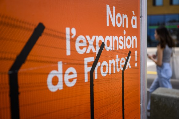 Une personne passe devant une affiche contre la participation financiere de la Suisse a l&#039;agence Frontex le mercredi 4 mai 2022 a Neuchatel. Le 15 mai 2022 les citoyennes et les citoyens suisses  ...