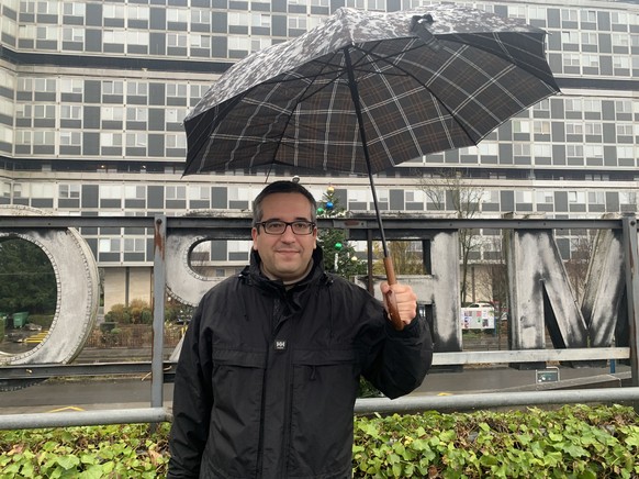 Howard Nobs, UDC, sous la pluie, face à une barre de la cité du Lignon. 3 décembre 2025.