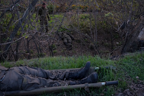 epa10244076 A Ukrainian soldier examines the bodies of two Russian soldiers found on the road from Kupiansk to Vuzlovyi, east of Kharkiv, Ukraine 14 October 2022. The Ukrainian army pushed Russian tro ...
