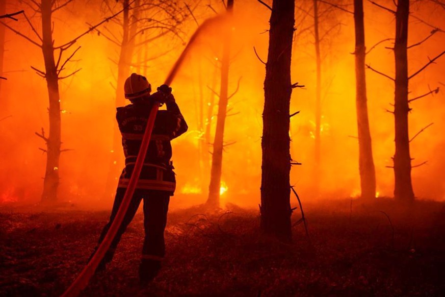 epa10079386 A handout photo made available by the Gironde Fire and Rescue Departmental Service 33 (SDIS 33) shows a firefighter battling a forest fire in La-Teste-de-Buch, France, 19 July 2022. The Gi ...