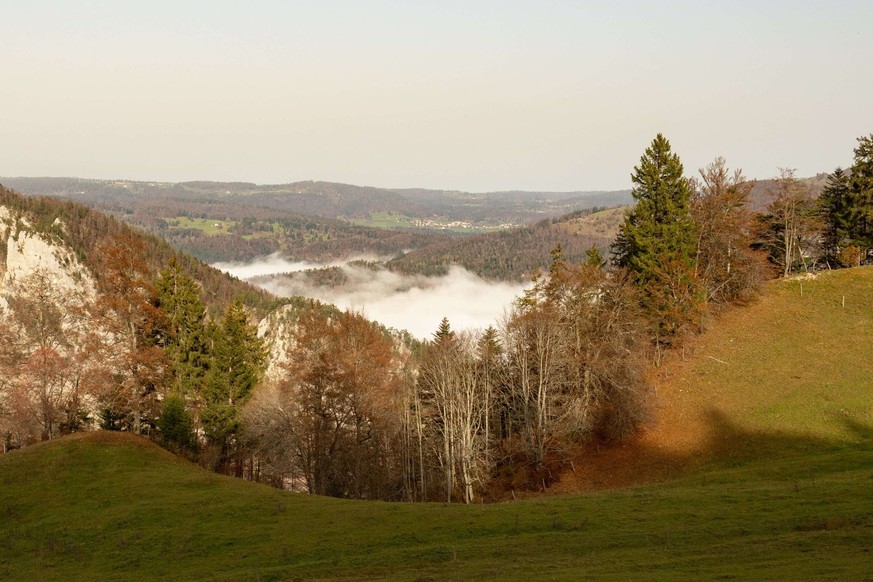 Une vue depuis un sentier de randonnée entre Frinvillier et le Chasseral, sur les collines et les vallées recouvertes de brouillard par une belle journée d&#039;automne.