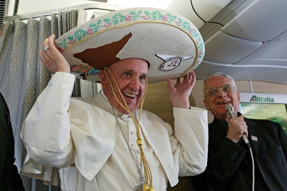epa05155977 Pope Francis wears a sombrero hat he received as a gift by a Mexican journalist aboard of the airplane to Havana, Cuba, 12 February 2016. Pope Francis visits Cuba and Mexico from 12 to 18 ...