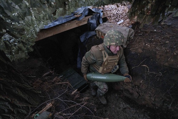 A Ukrainian serviceman of 14th National Guard &quot;Chervona Kalyna&quot; brigade carries artillery shell before firing towards Russian positions at the frontline on Pokrovsk direction, Donetsk region ...