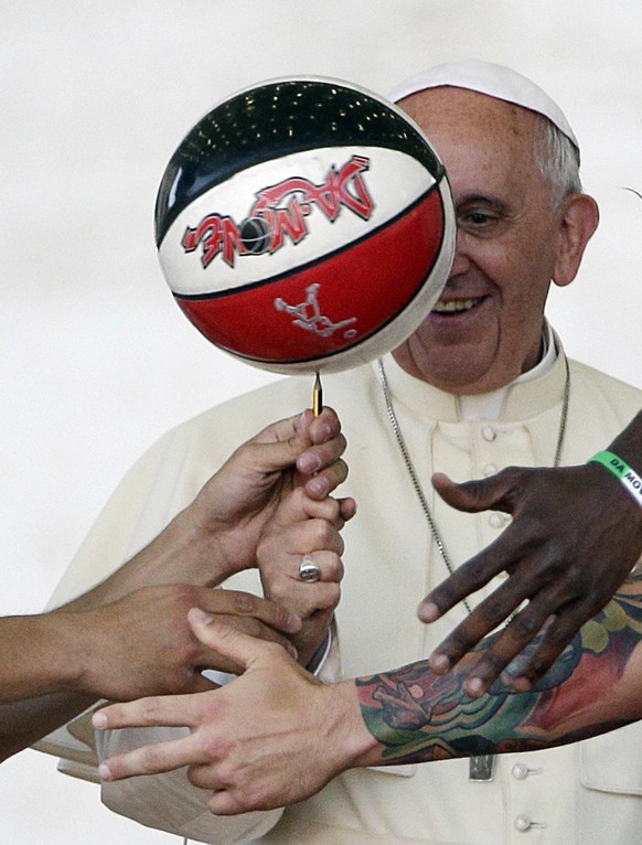 Pope Francis is helped by basketball players to keep the balance of a ball during during a meeting with the members of the Italian Sports Center in St. Peter's Square at the Vatican Saturday, Jun ...