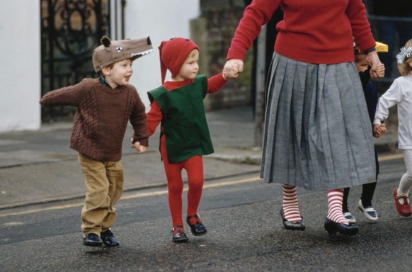 Prince Harry, dressed as an elf (or possibly a Christmas sprite) ahead holds the hand of a woman on his way to appear in Mrs Mynors Nursery School nativity play in London, England. 9th December 1987.  ...