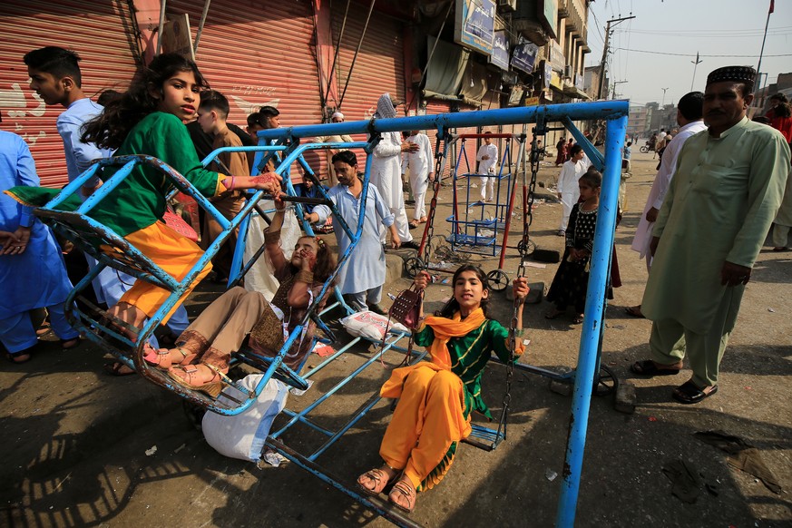 epa09922396 Children enjoy riding a swing during Eid al-Fitr celebrations in Peshawar, Pakistan, 02 May 2022. Muslims around the world are celebrating Eid al-Fitr, the three day festival marking the e ...