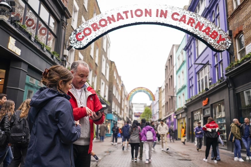 Des gens regardent leur téléphone dans Carnaby Street, à Londres, dimanche.