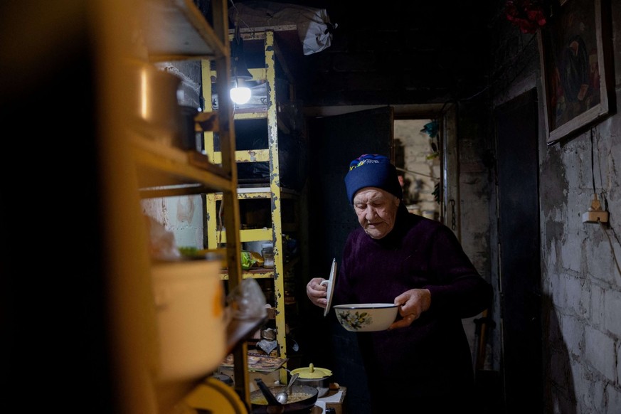 Lidia Isayeva, 86 ans, tient une assiette dans la cave où elle vit dans son immeuble lourdement endommagé dans la ville de Lyman, près de la ligne de front dans la région de Donetsk, le 7 mai 2025, lo ...
