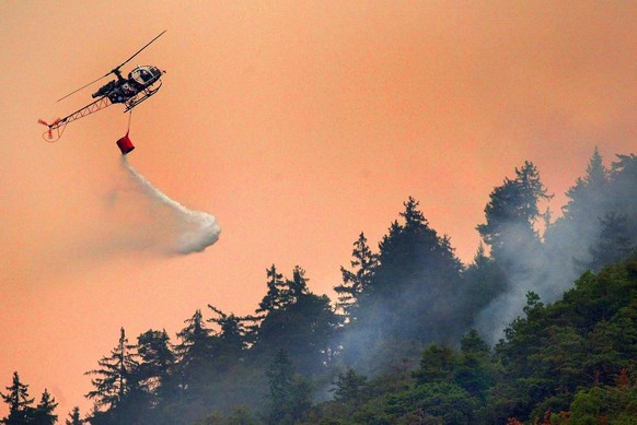 A helicopter fights against a wildfire, Thursday, August 14, 2003 at the border of the Swiss village of Leuk in southern Switzerland. Due to the drought, several wildfires erupted over the last days i ...