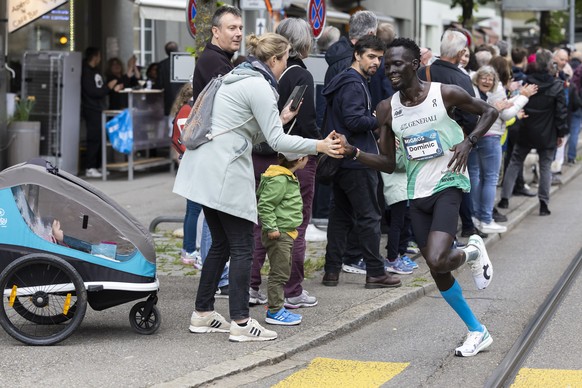 Dominic Lobalu klatscht mit einer Zuschauerin ab, waehrend dem traditionellen 10 Meilen Grand Prix von Bern, am Samstag, 13. Mai 2023, in Bern. (KEYSTONE/Peter Klaunzer)