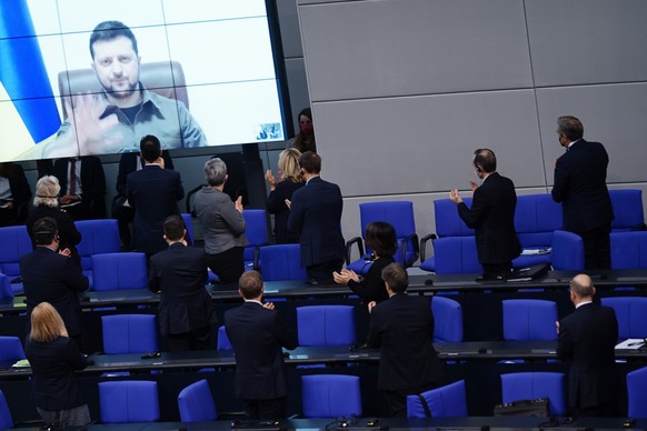 epa09830538 Ukrainian President Volodymyr Zelensky waves as he receives applause after delivering a video address to the German parliament in Berlin, Germany, 17 March 2022. Ukrainian President Volody ...