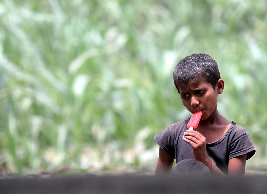 Un garçon prend une glace pendant un après-midi chaud dans la banlieue de New Delhi, en Inde, le 1er mai 2022.