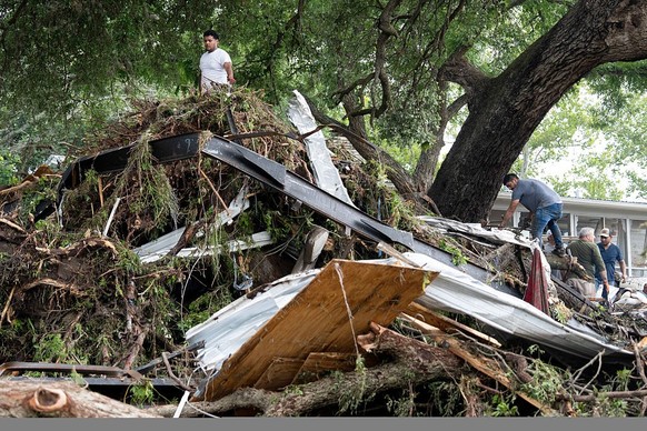 KERRVILLE, TEXAS JULY 5: Volunteers and neighbors work to removed the remains of a trailer and other property debris from damaged trees along the Guadalupe River after heavy rain in Kerville, Saturday ...