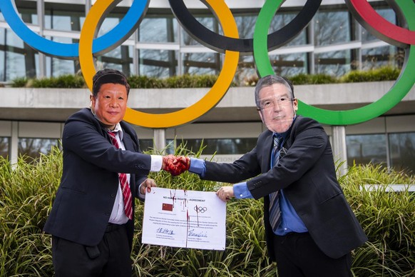 Protesters with masks of Chinese President Xi Jinping and International Olympic Committee, IOC, President Thomas Bach, shake hands during a protest against Beijing 2022 Winter Olympics by activists of ...