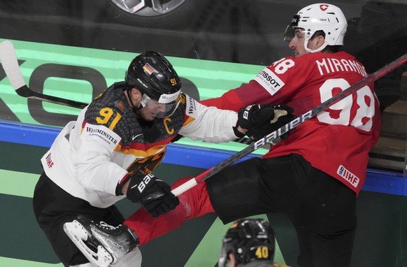 Moritz Muller of Germany, left, fights for a puck with Marco Miranda of Switzerland during the quarterfinal match between Germany and Switzerland at the ice hockey world championship in Riga, Latvia,  ...