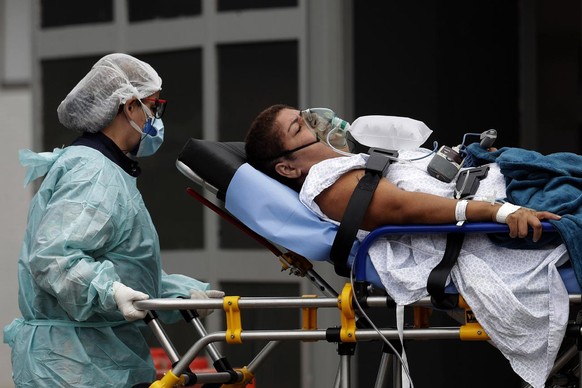 A healthcare worker transfers a patient suspected of having COVID-19 from an ambulance to the HRAN public hospital in Brasilia, Brazil, Thursday, April 29, 2021. (AP Photo/Eraldo Peres)