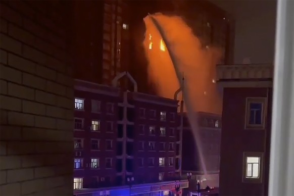 In this image taken from video, firefighters spray water on a fire at a residential building in Urumqi in western China&#039;s Xinjiang Uyghur Autonomous Region, Thursday, Nov. 24, 2022. A fire in an  ...