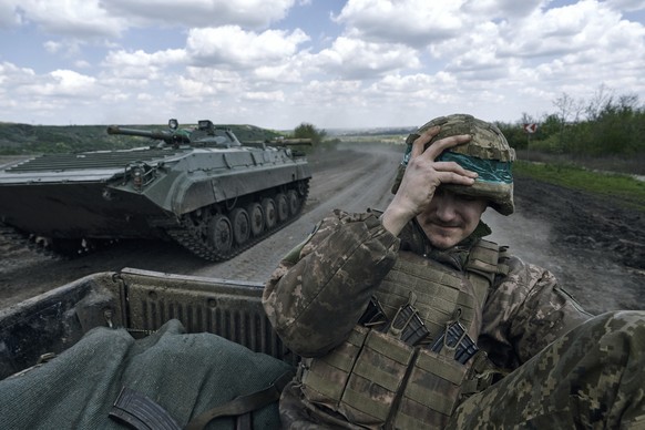A Ukrainian soldier holds his helmet as he rides in an APC in Bakhmut, in the Donetsk region, Ukraine, Wednesday, April 26, 2023. (AP Photo/Libkos)
