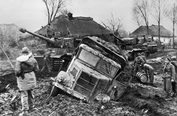 Ein im Schlamm eingesunkener Lastwagen der Waffen-SS wird im Januar 1944 an einem Abschnitt der Ostfront entladen, um ihn spaeter mit einem der drei deutschen Kampfpanzer vom Tiger I, im Hintergrund,  ...