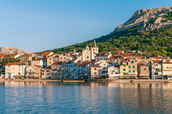 Landschaftliches Küstendorf mit Bergkulisse und historischen Gebäuden. Baška, Insel Krk, Kroatien.