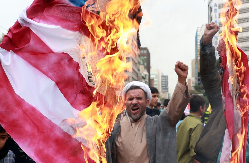epa11698409 An Iranian cleric chants slogans as Iranians burn a US flag during an anti-US rally marking the 45th anniversary of the US Embassy takeover, in front of the former embassy building in Tehr ...