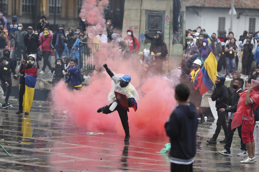 An anti-government protester returns a tear gas canister at the police during clashes in Bogota, Colombia, Wednesday, May 5, 2021. The protests that began last week over a tax reform proposal continue ...