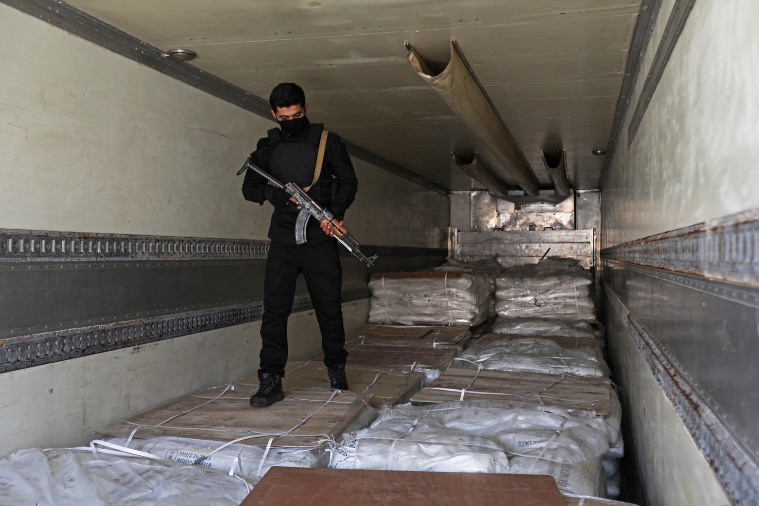 Un membre des forces de sécurité des nouvelles autorités syriennes monte la garde sur des boîtes de pilules de Captagon trouvées dans un complexe des forces du président déchu Bachar al-Assad à Damas  ...