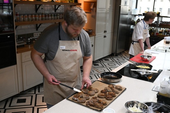 A participant prepares beef cutlets during the "Lunch a la Russe" master class at the Novikov cooking school in Moscow on April 16, 2026. (Photo by Igor IVANKO / AFP)