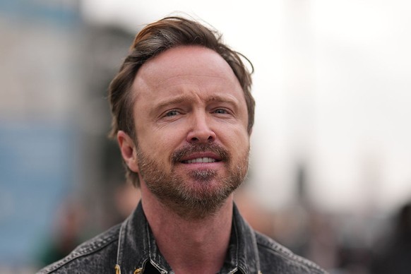 PARIS, FRANCE - JANUARY 2026: Aaron Paul wears short brown hair with a side part, a black washed denim overshirt with a pointed collar and flap chest pockets with metal snap buttons, outside Schiapare ...
