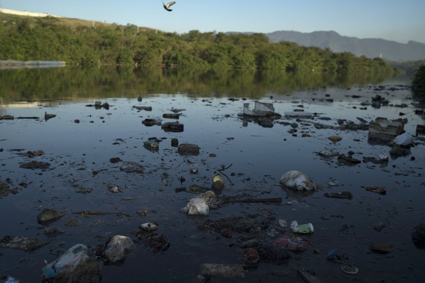 Trash floats on the water next to a barrier in a canal at the Mare slum complex in Rio de Janeiro, Brazil, Friday, July 31, 2015. In Rio, much of the waste runs through open-air ditches to fetid strea ...