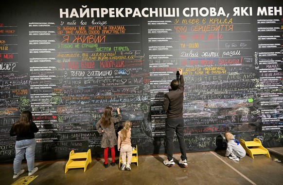 A family jumps in an artificial puddle during a visit at the &quot;Third Wind. Emotions and Feelings&quot; interactive exhibition in Kyiv, on April 27, 2025. The exhibition, at the discretion of the o ...