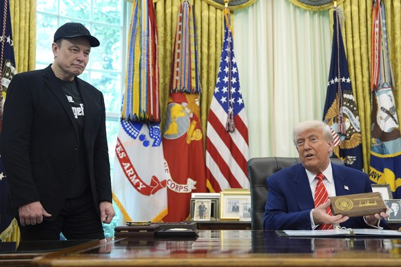 President Donald Trump speaks as he holds a box containing a key before presenting it to Elon Musk, left, during a news conference in the Oval Office of the White House, Friday, May 30, 2025, in Washi ...
