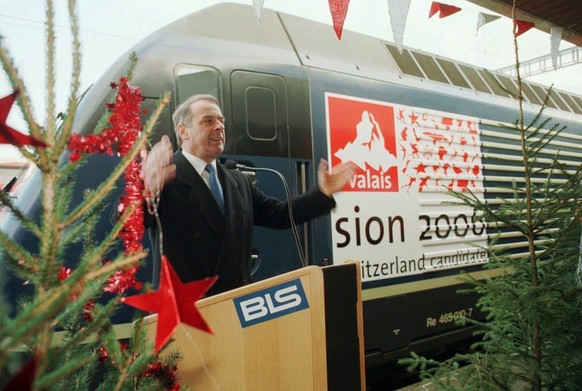 Bundesrat Adolf Ogi wirbt am Montag den 21. Dezember 1998 in Bern, vor einer BLS Lok mit dem Logo von Sion 2006 fuer die Olympischen Spiele in der Schweiz . Die Bern Loetschberg Simplon Bahn (BLS) unt ...